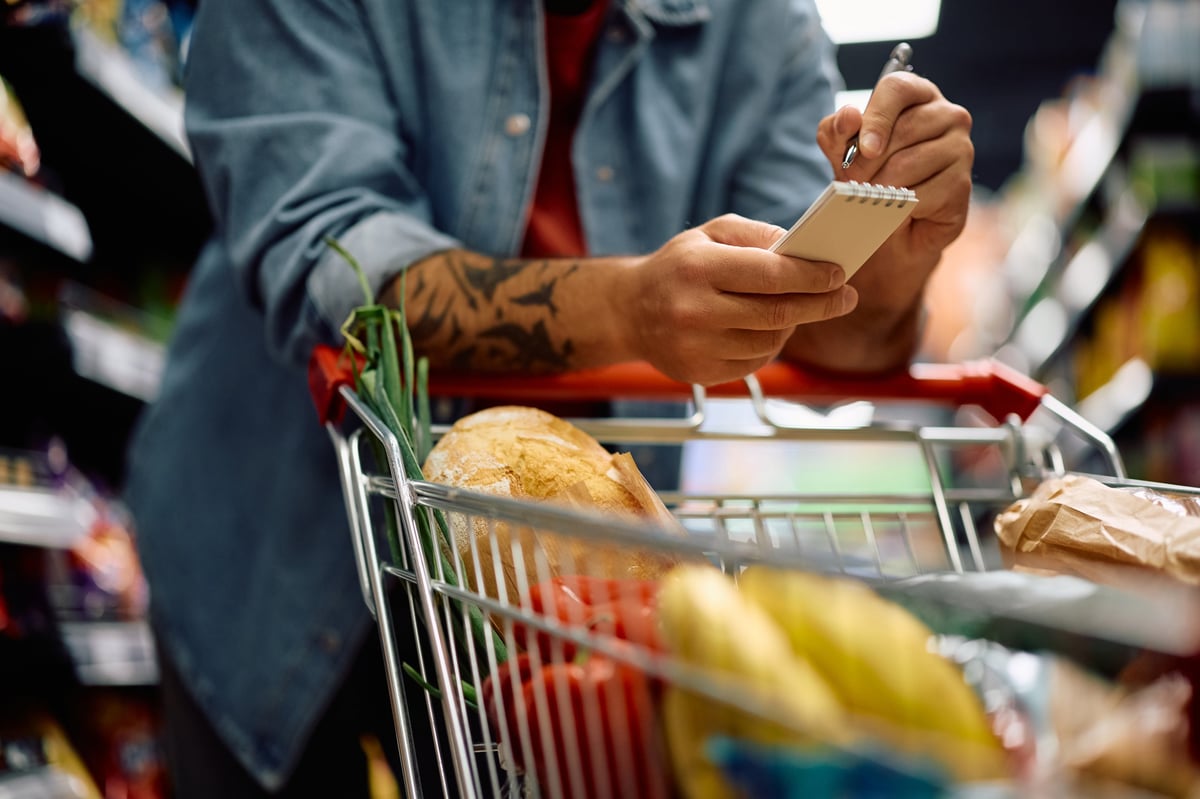 Man going through his Grocery LISS list while shopping in a supermarket